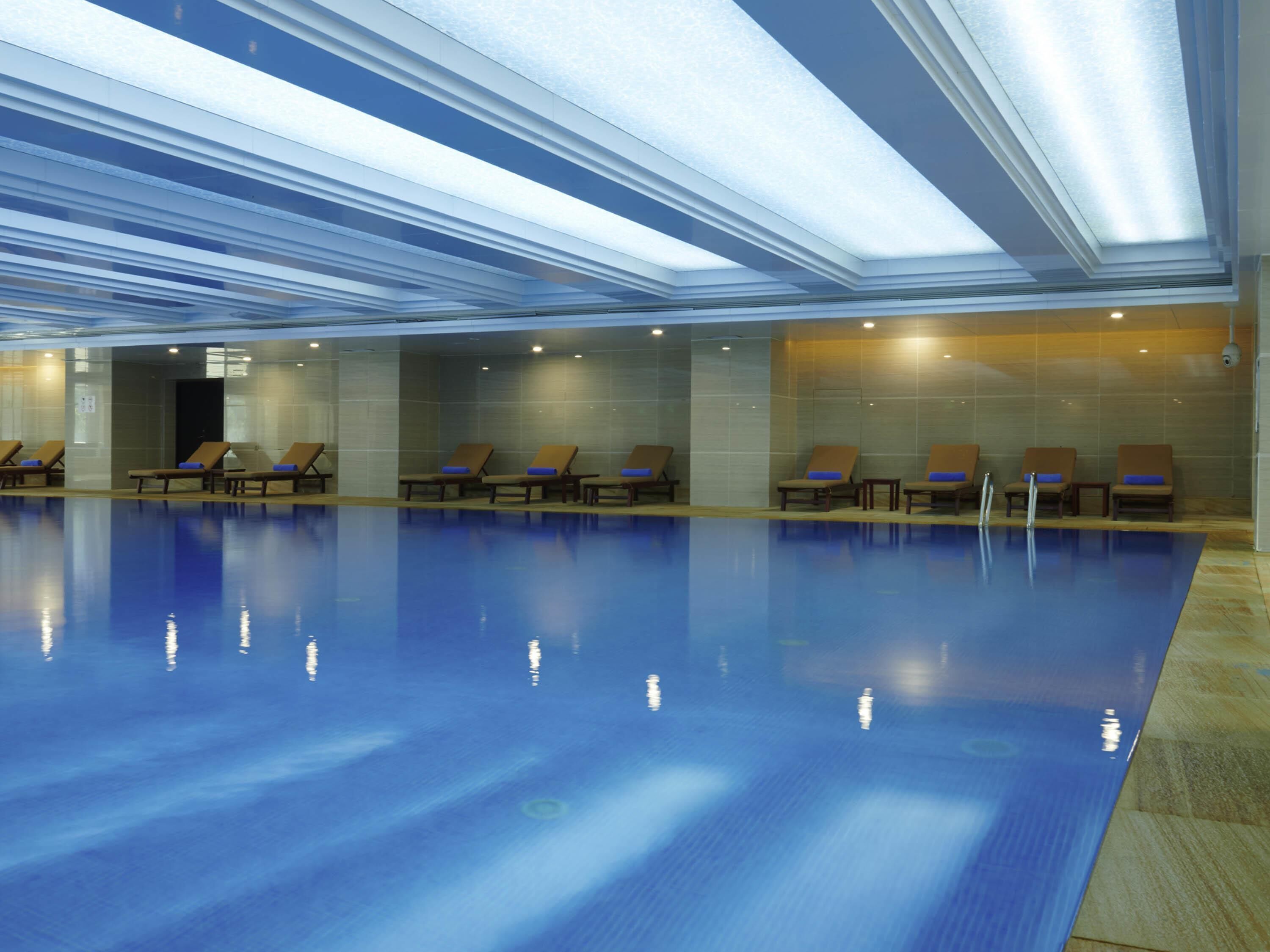 A swimming pool with lounge chairs and a ceiling with skylights.