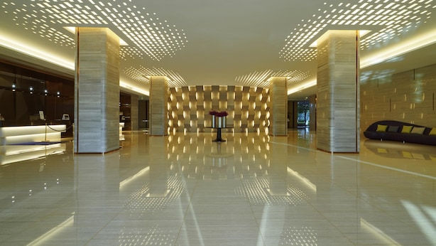 Un vestíbulo amplio con piso reflectante, una recepción y un área de descanso.