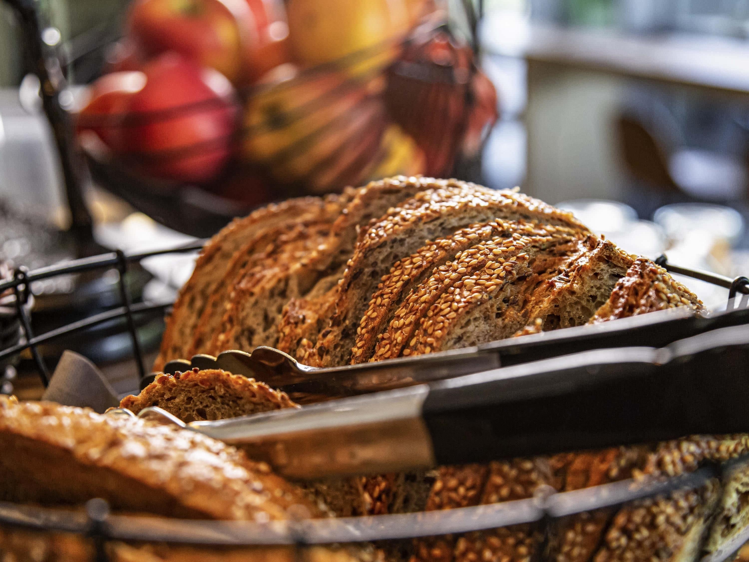 A loaf of multi-grain bread with seeds on a wire rack.