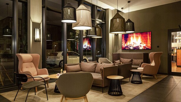 Un área de estar moderna con sofás, sillones e iluminación colgante.