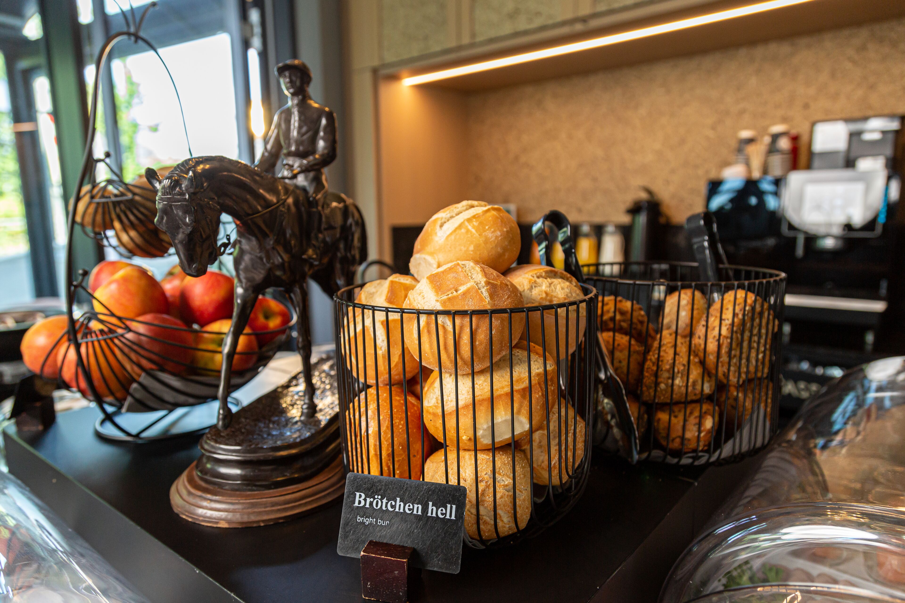A display of bread and apples in a basket, with a sign reading "Brötchen hell".