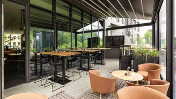 An outdoor dining area with tables and chairs, a TV, and a grill.