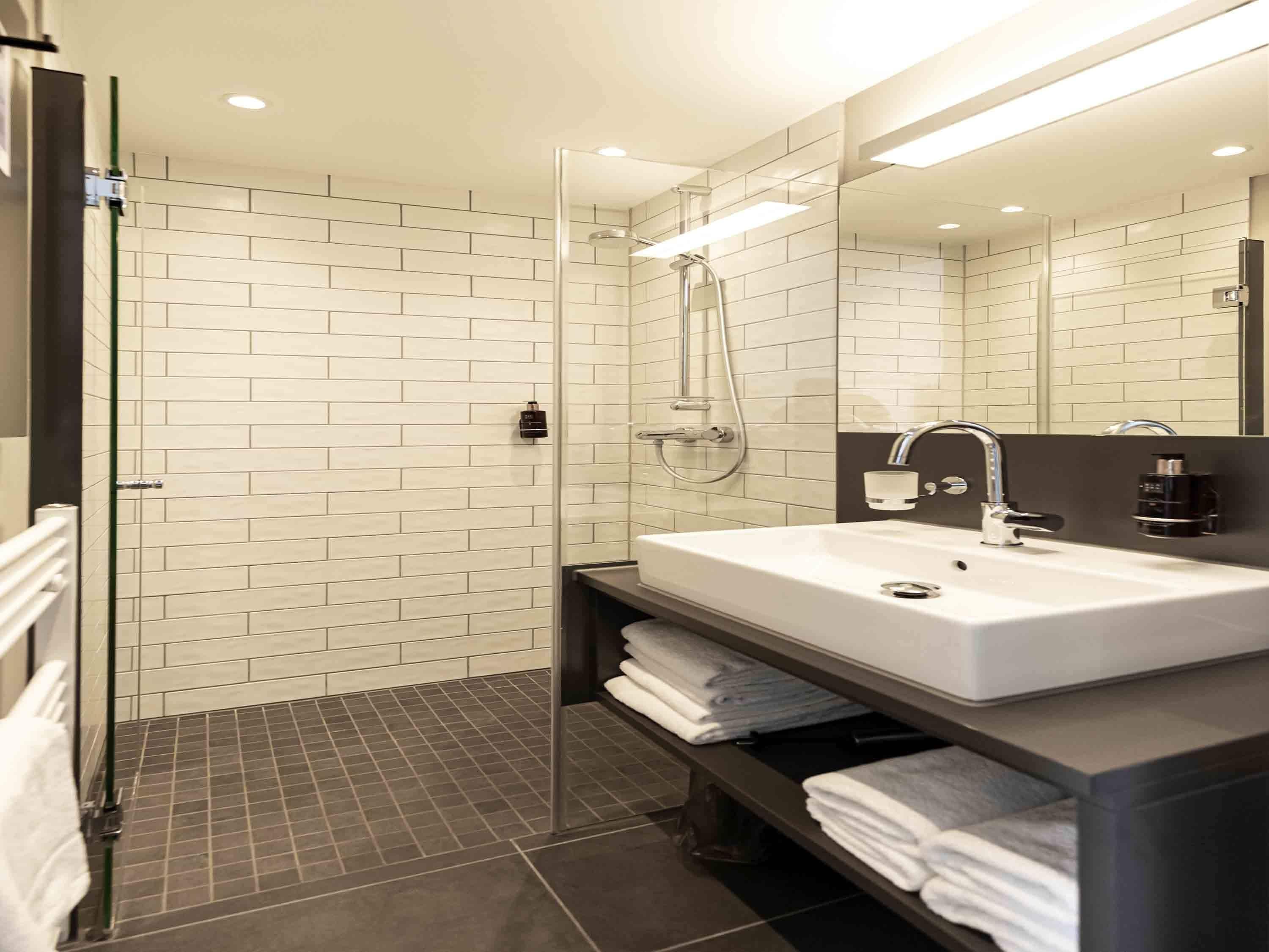 A modern bathroom with a glass-enclosed shower, a white sink with a black countertop, and a mirror above the sink.