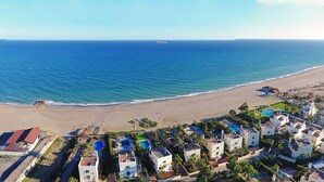 Vista aérea de una zona costera con playa, puerto deportivo y edificios residenciales.