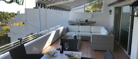 A rooftop terrace with a dining table set for two, outdoor seating, and a view of the surrounding area.