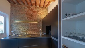 A modern kitchen with a brick wall, a gas stove, a sink, and a wine rack. - Apartments Florence - Santo Spirito Exclusive (Firenze)