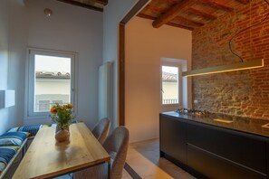A modern kitchen with a brick wall, a wooden dining table with chairs, and a view through the window.
