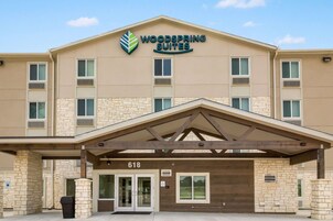 Un hotel con fachada de piedra, un acceso cubierto y un letrero que dice "Woodspring Suites".