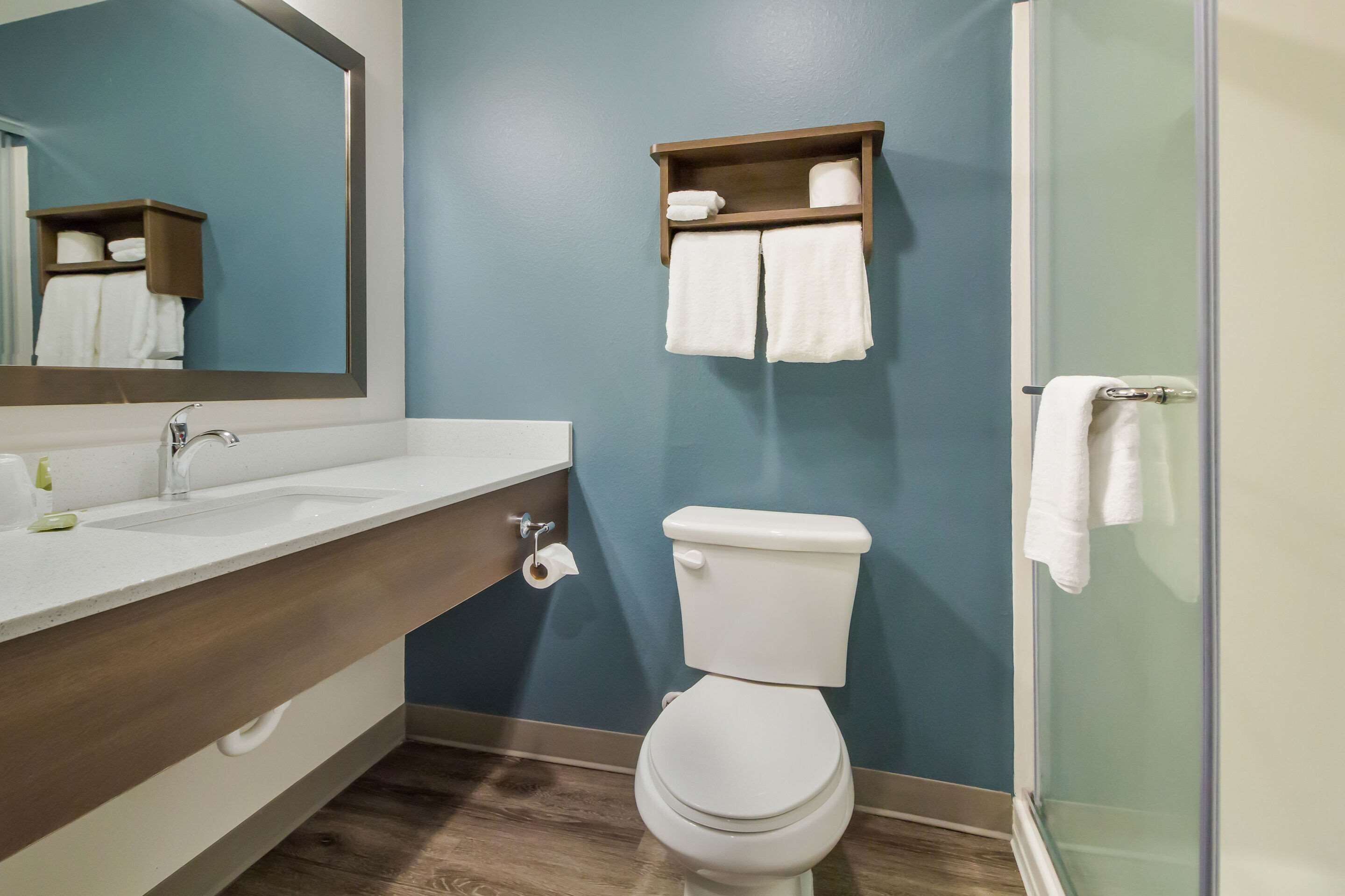 Un baño con lavamanos blanco, inodoro, toallero y espejo.