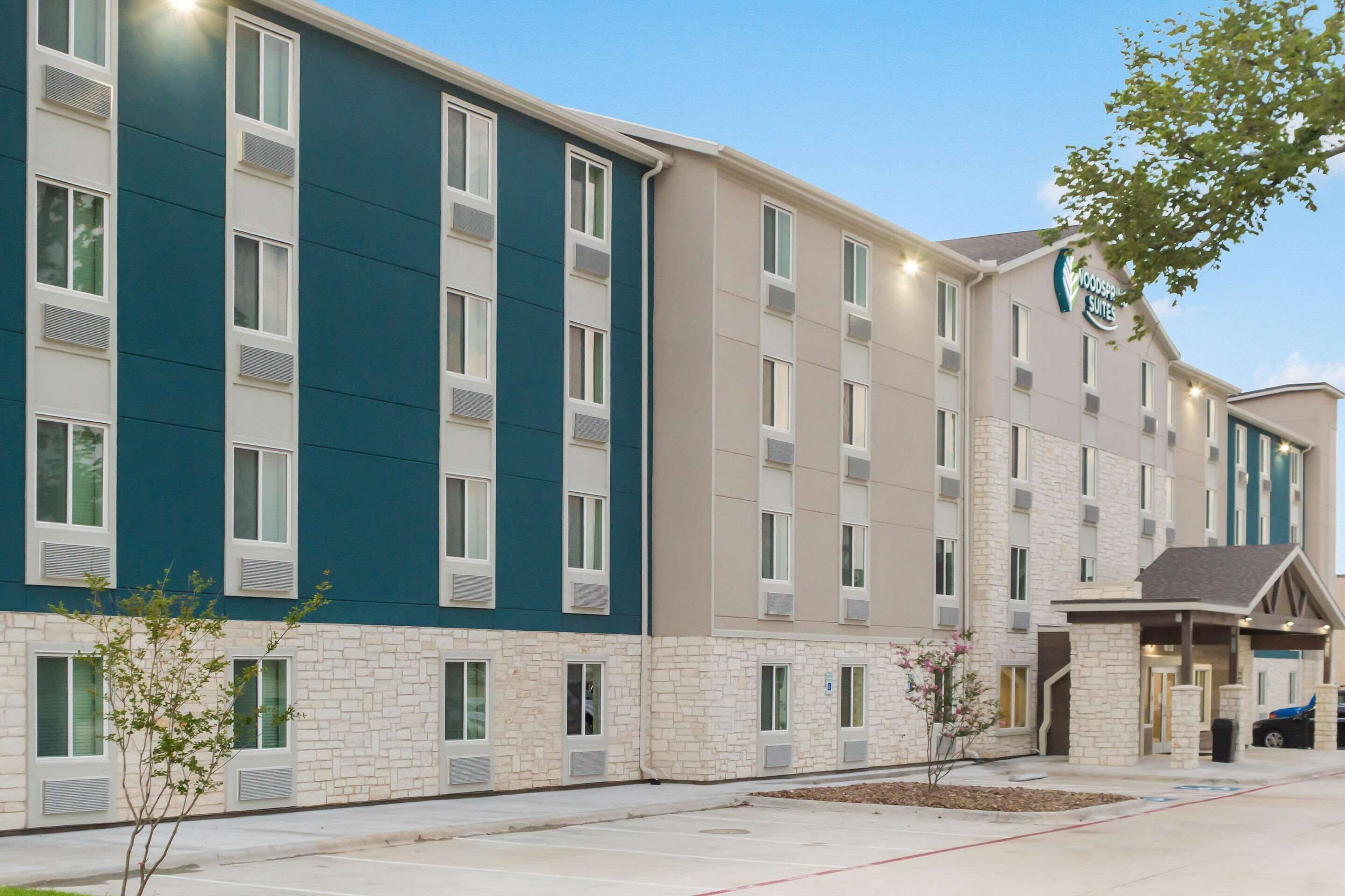 A multi-story hotel with a modern design, featuring a mix of stone and painted exteriors, and a prominent entrance with a covered area.