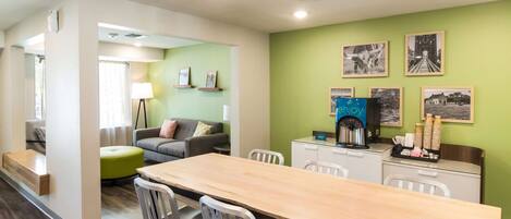 Una habitación de hotel moderna con comedor, sofá y estación de café.