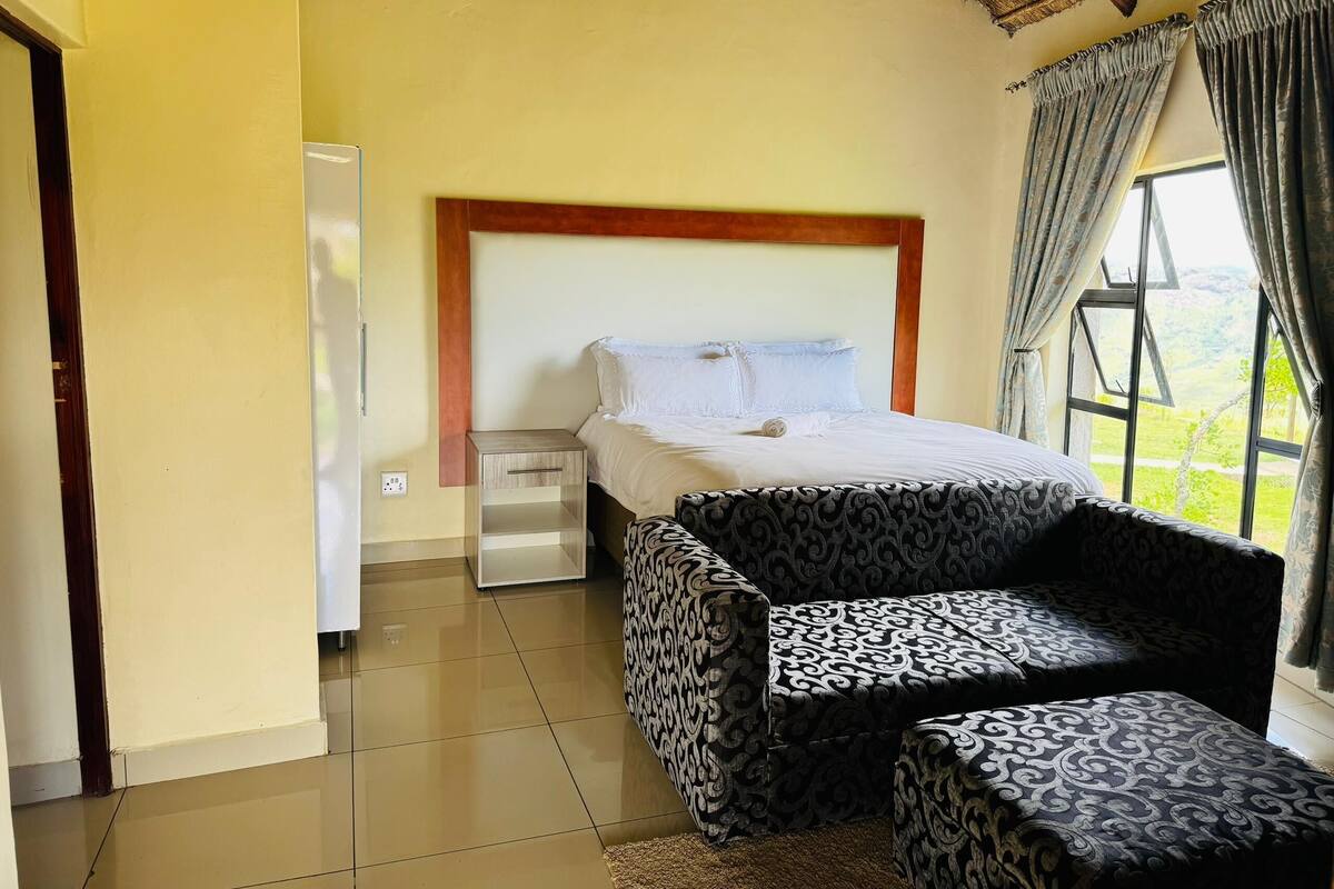 A bedroom with a bed, bedside table, and a patterned sofa.