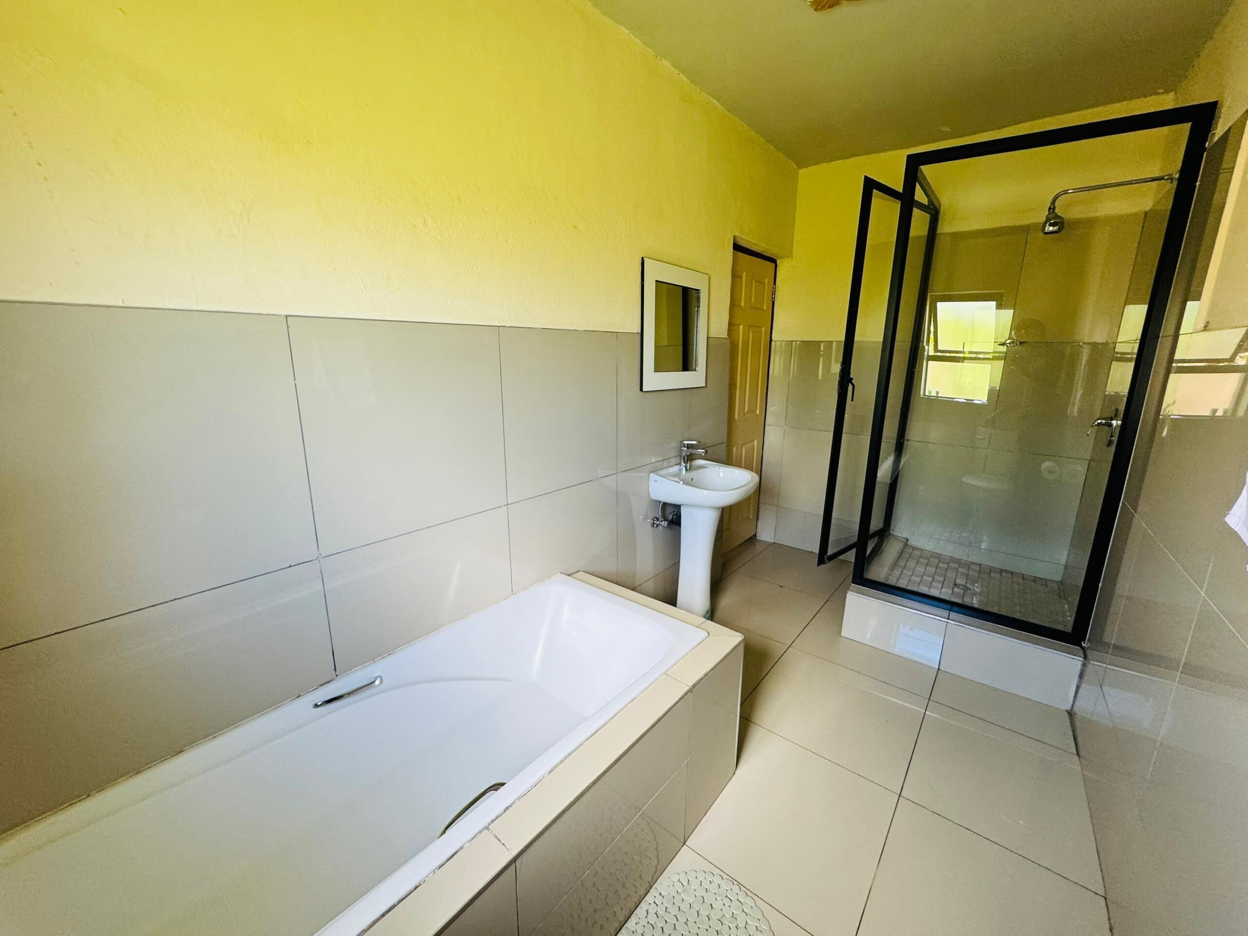 A bathroom with a bathtub, sink, and glass shower enclosure.