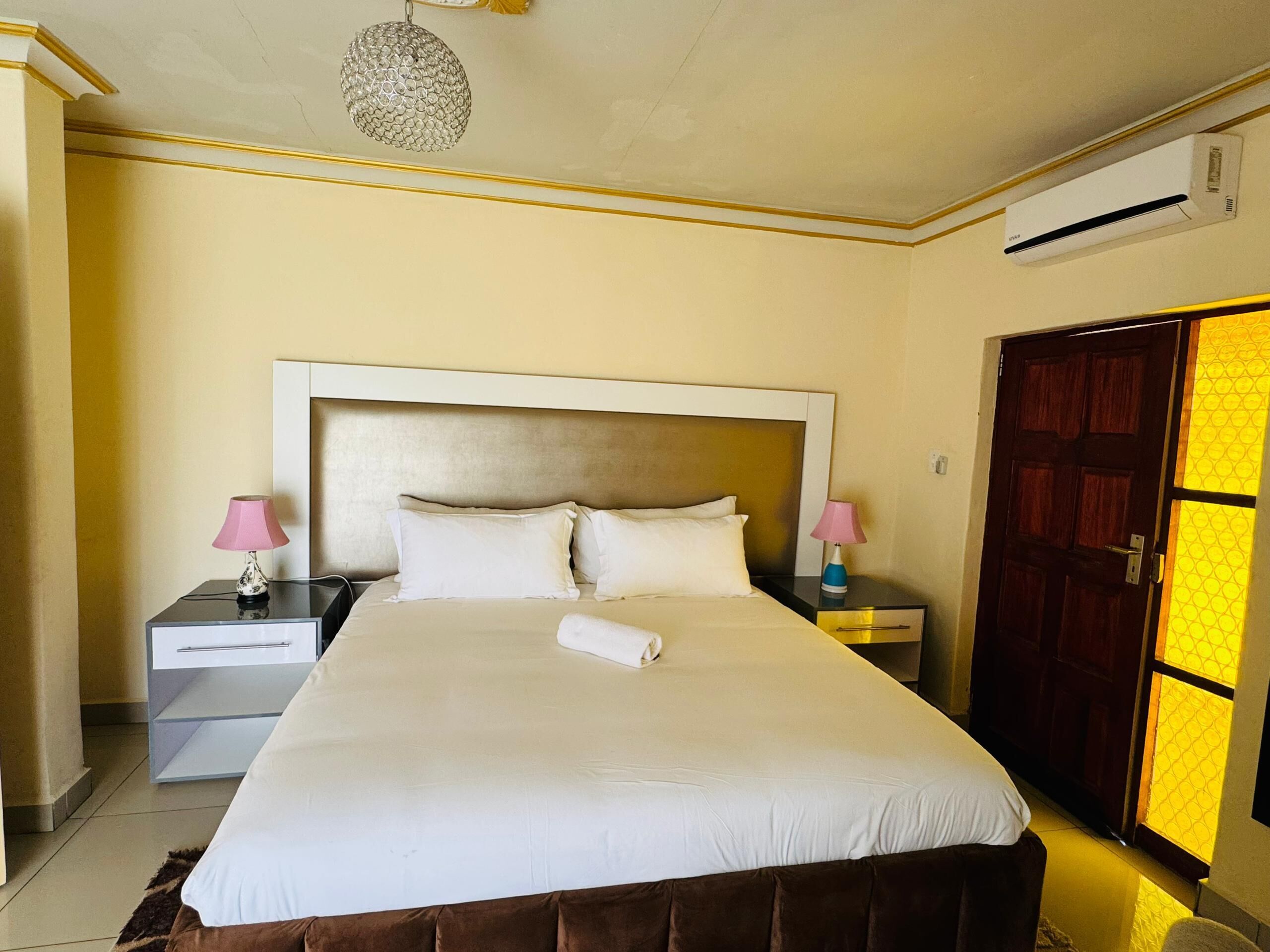 Habitación de hotel con una cama grande, dos mesitas de noche, un armario y un equipo de aire acondicionado.
