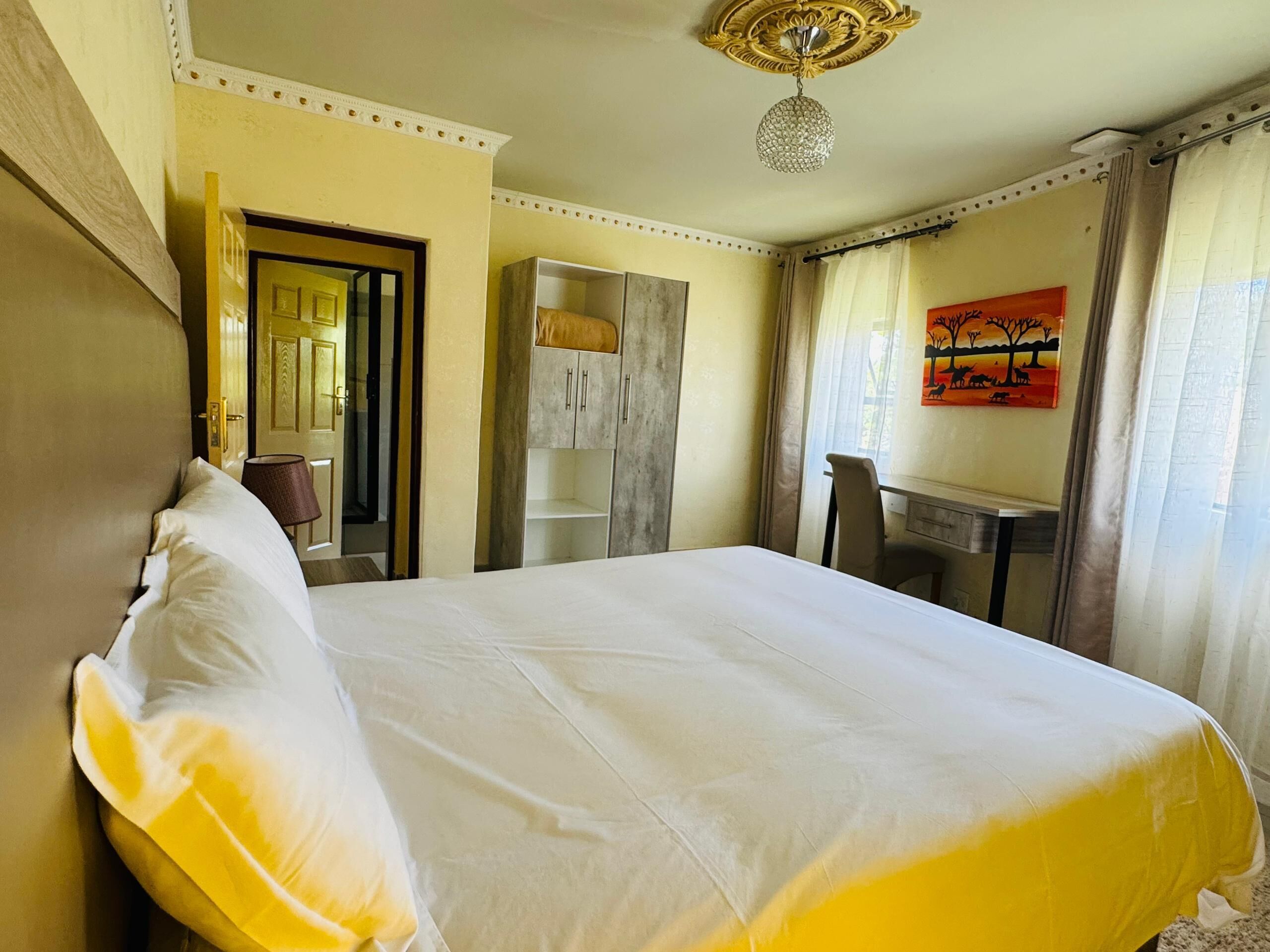Une chambre d’hôtel avec un grand lit, un bureau, une armoire et un tableau au mur.