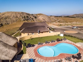 Un resort con piscina, zona de estar al aire libre y edificio con techo de paja.