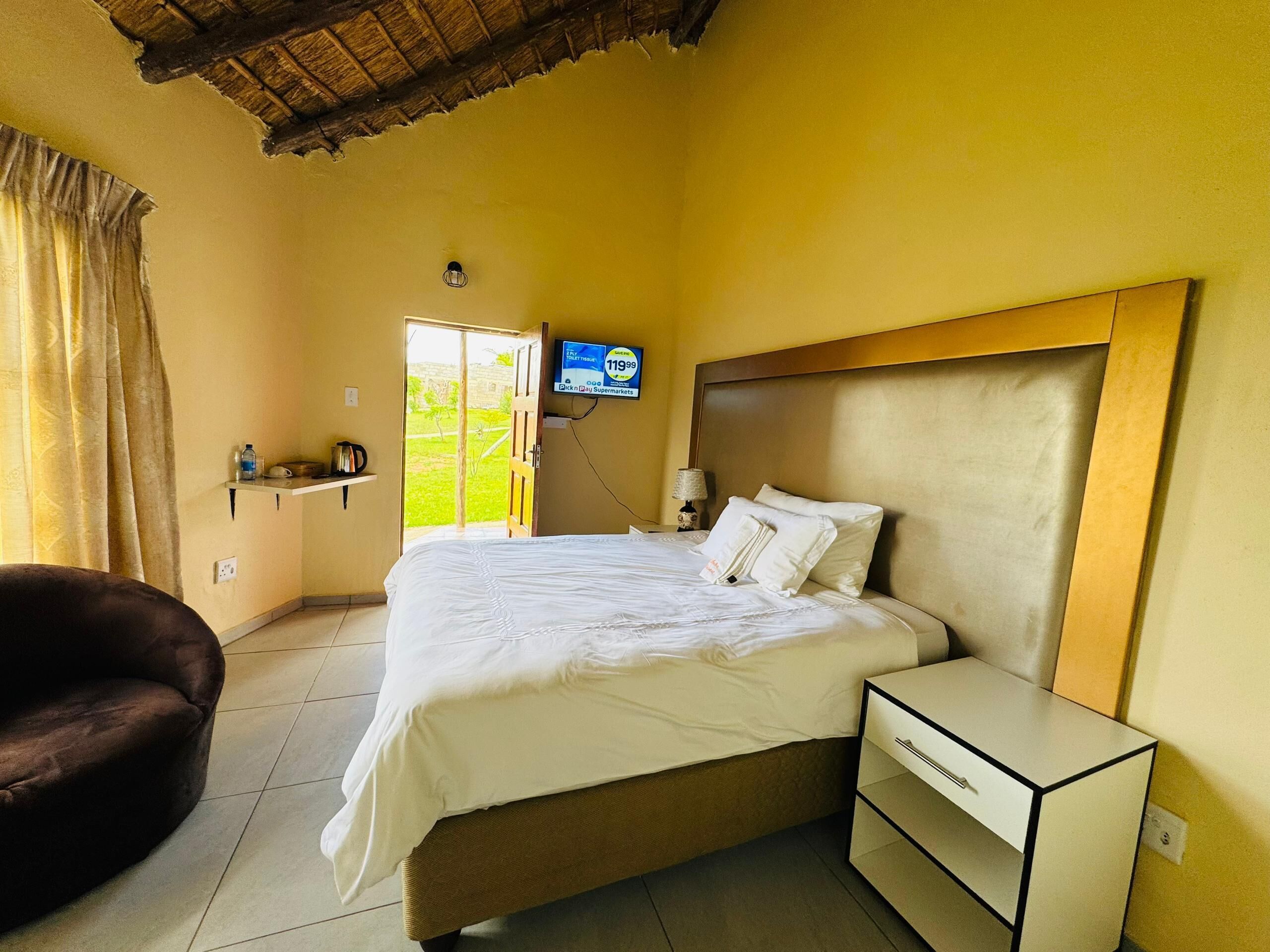 Une chambre d’hôtel avec un lit, une table de chevet, une télévision et une chaise.