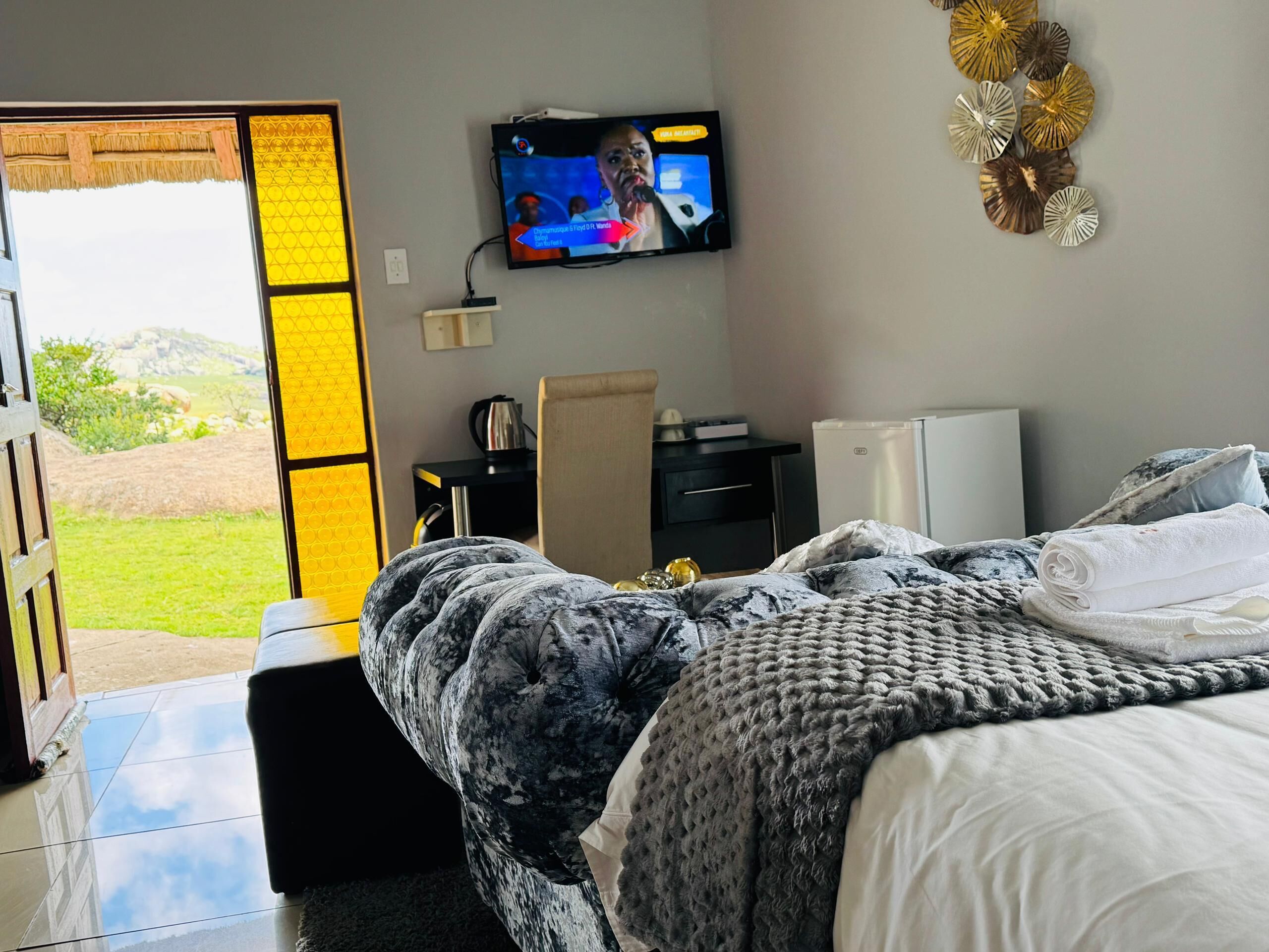 A bedroom with a bed, a television, a desk, and a view of the outdoors.