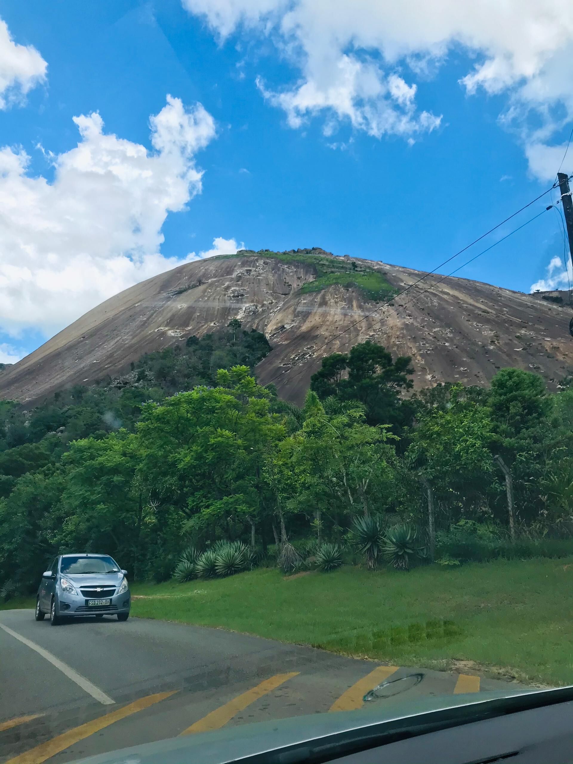 A car driving on a road with a mountain in the background.