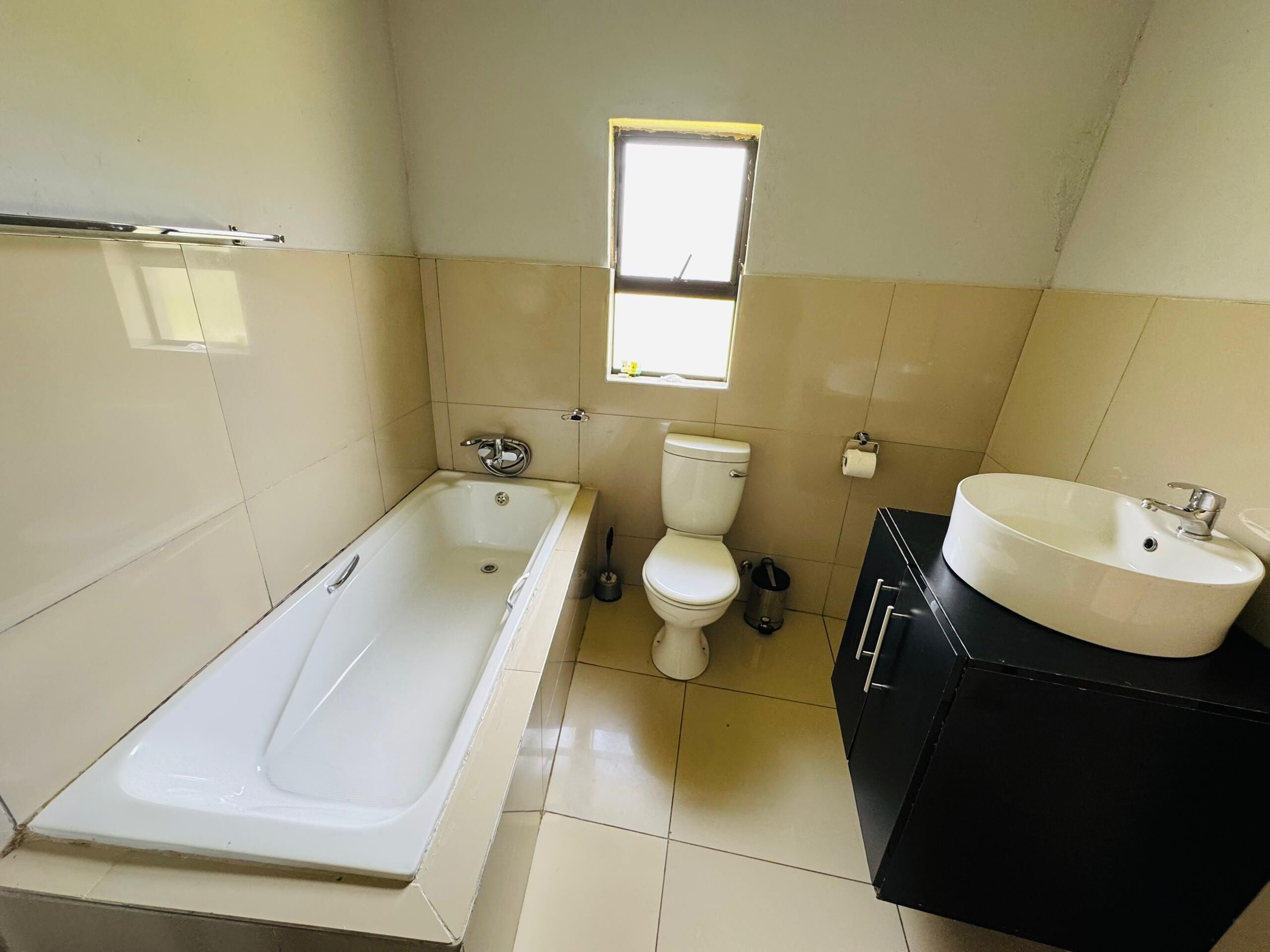 A bathroom with a bathtub, toilet, sink, and a window.