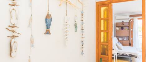 A room with a bed, a wooden door, and a wall with hanging decorations.