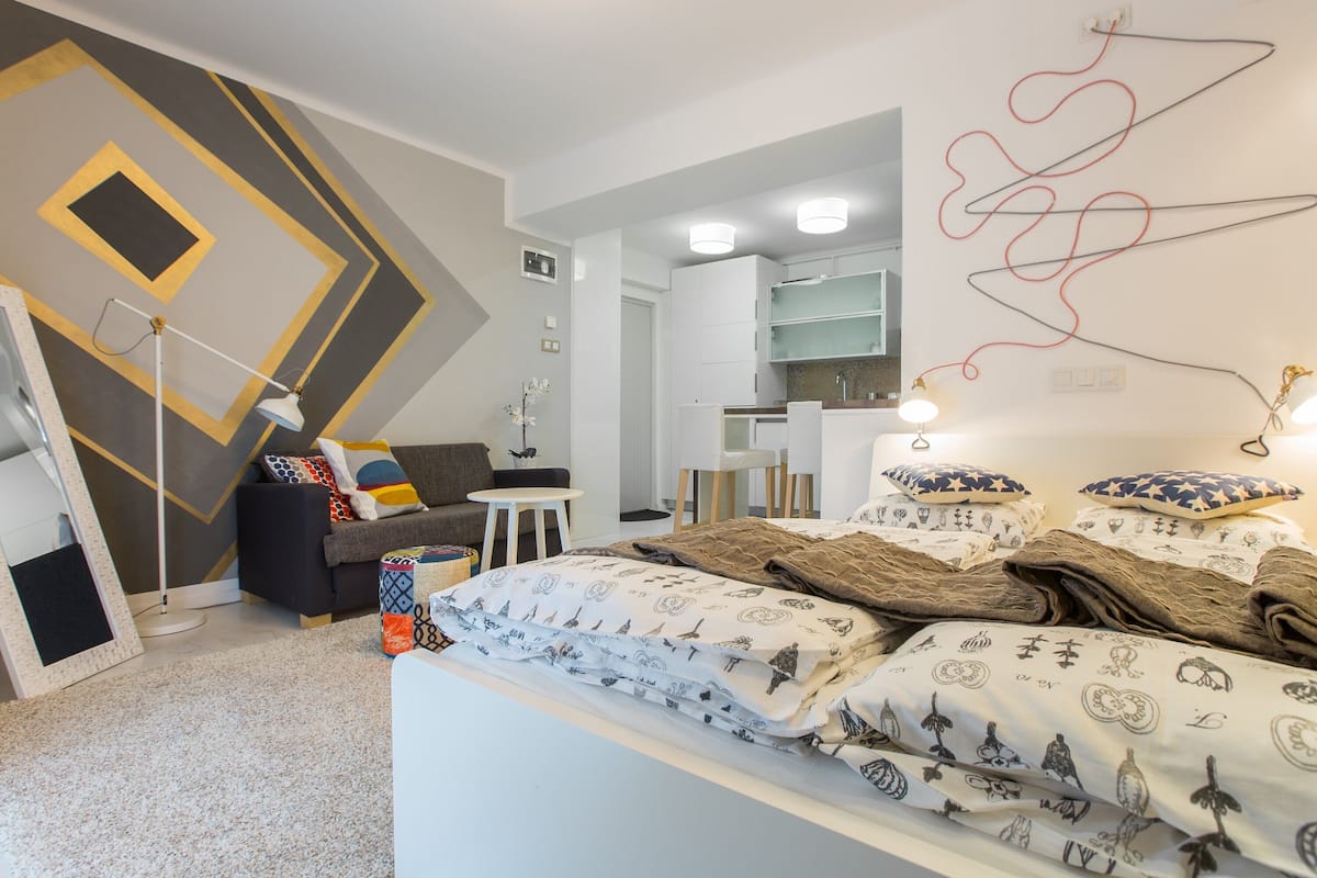 A modern bedroom with a bed, bedside tables, a dresser, and a mirror.