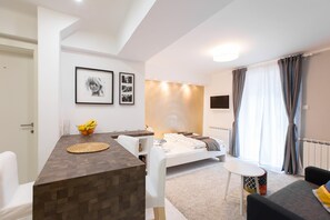 Een moderne slaapkamer met een bed, nachtkastje en een zithoekje.