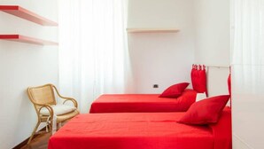 A room with two beds, a chair, and a window with curtains. - Opera Luxury Terrace (Rome)