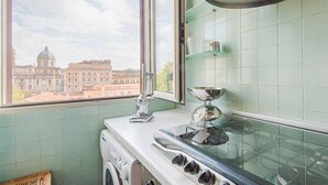 A kitchen with a window, a washing machine, and a stove. - Opera Luxury Terrace (Rome)