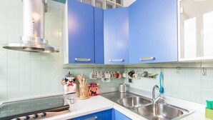 A kitchen with blue cabinets, a stainless steel sink, and a stove. - Opera Luxury Terrace (Rome)