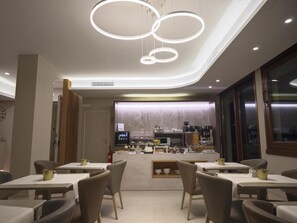 A modern restaurant interior with a central counter, tables, and chairs. - Albergo Grappolo D'oro (Montebelluna)