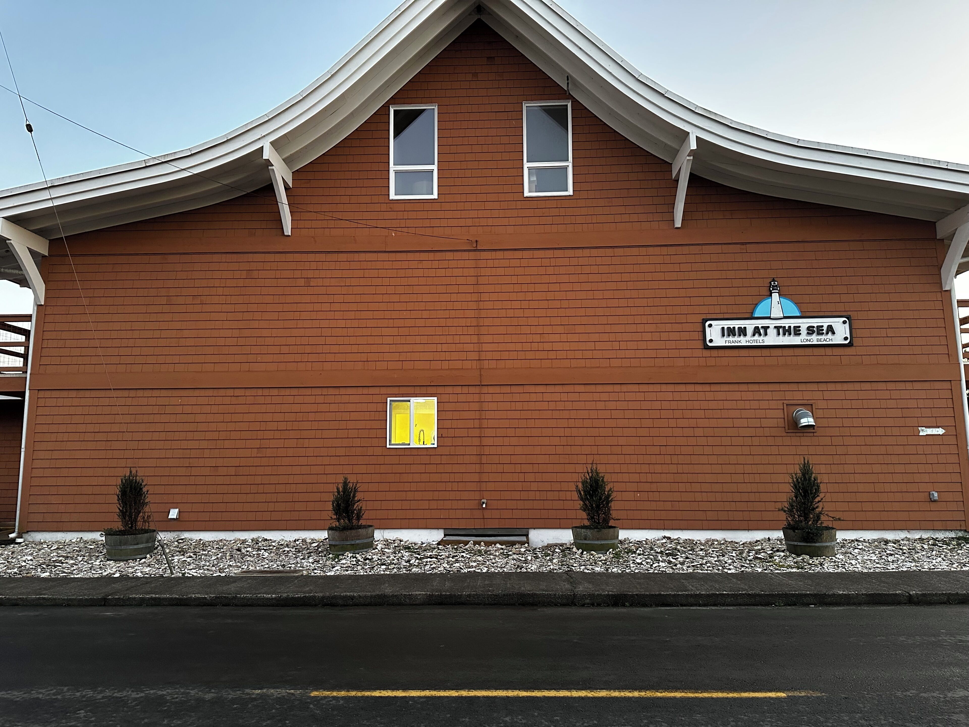 A building with a sign reading "Inn at the Sea" and a small window with a yellow sign.