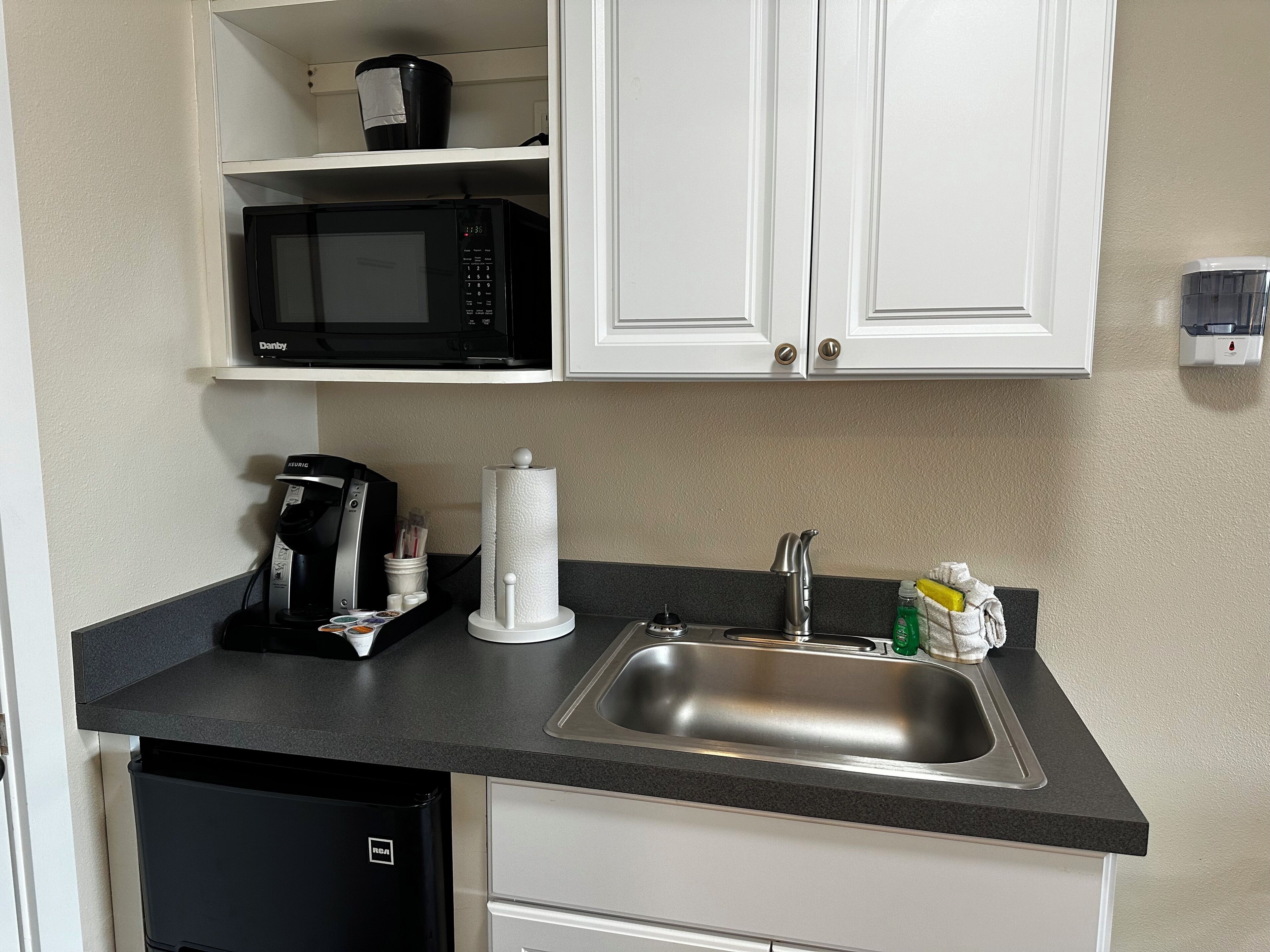 A compact kitchen with a microwave, coffee maker, and sink.