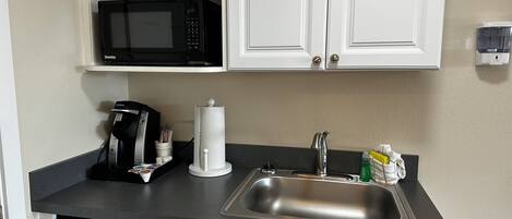 A compact kitchen with a microwave, coffee maker, and sink.