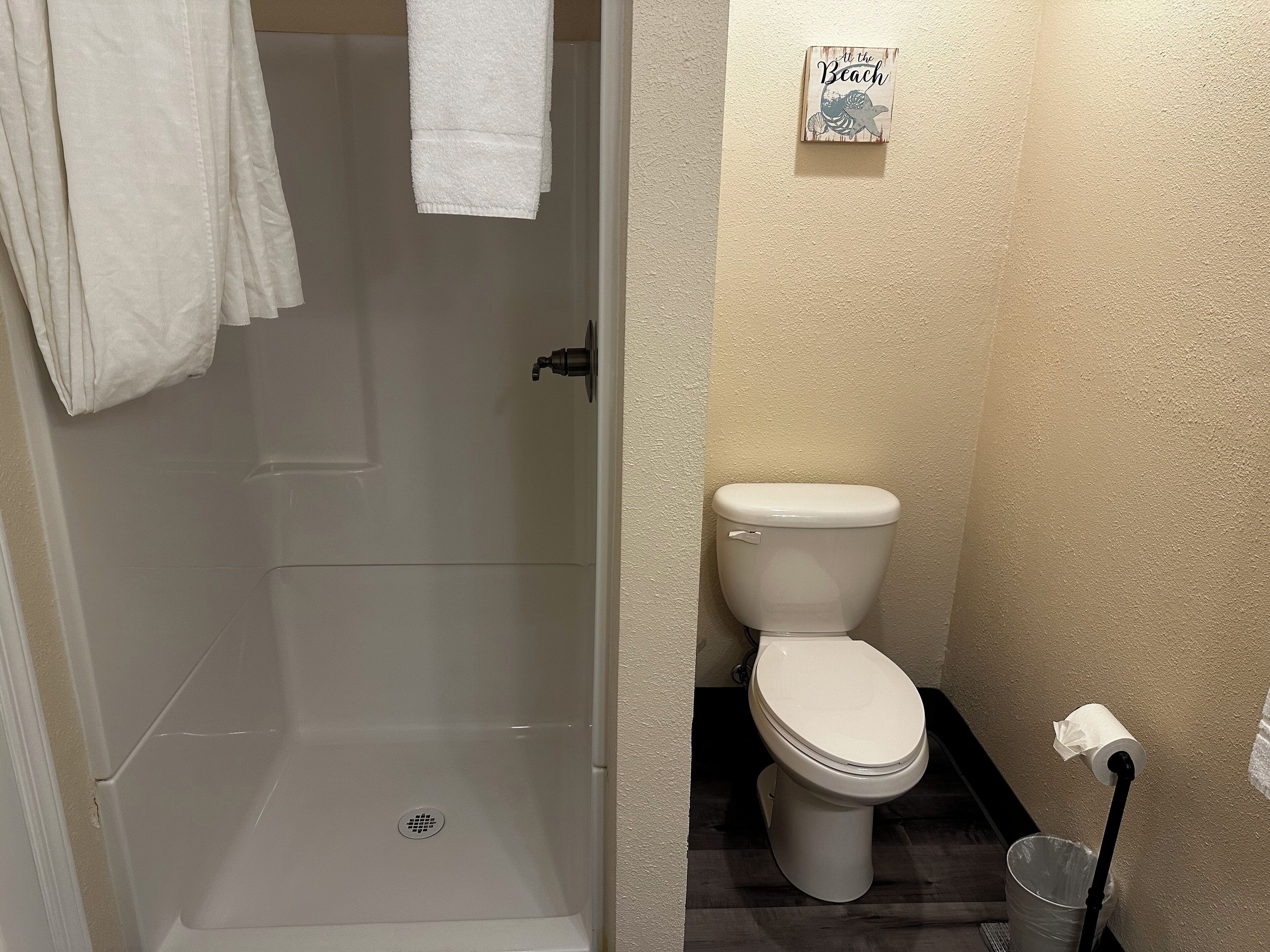 A bathroom with a toilet, a shower, and a towel rack.