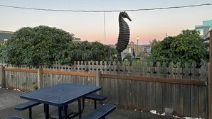 Ein Garten mit einem Metalltisch, Bänken, einem Holzzaun und einer großen Skulptur eines Meerestitanes.