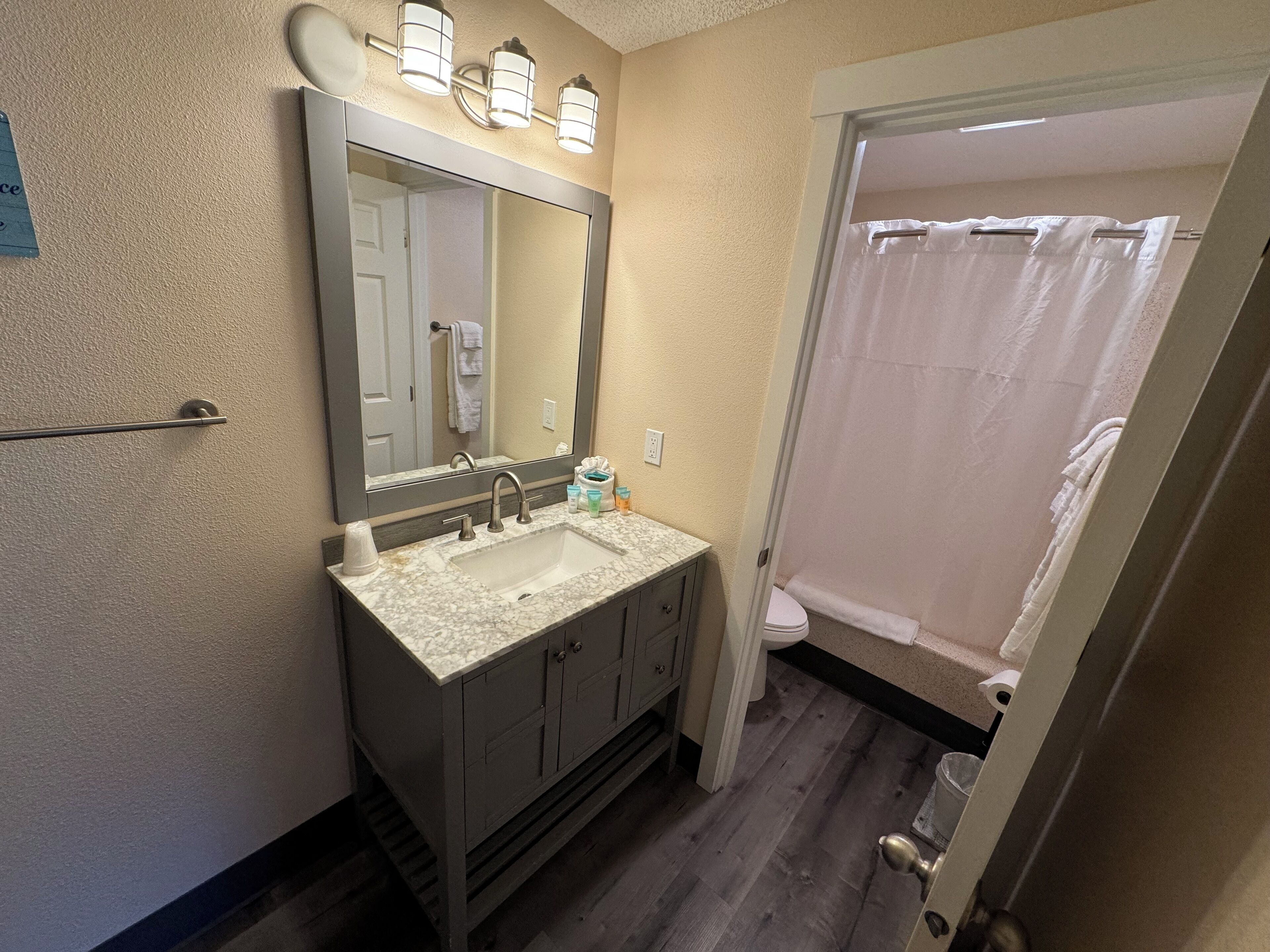 A bathroom with a sink, mirror, and shower curtain.