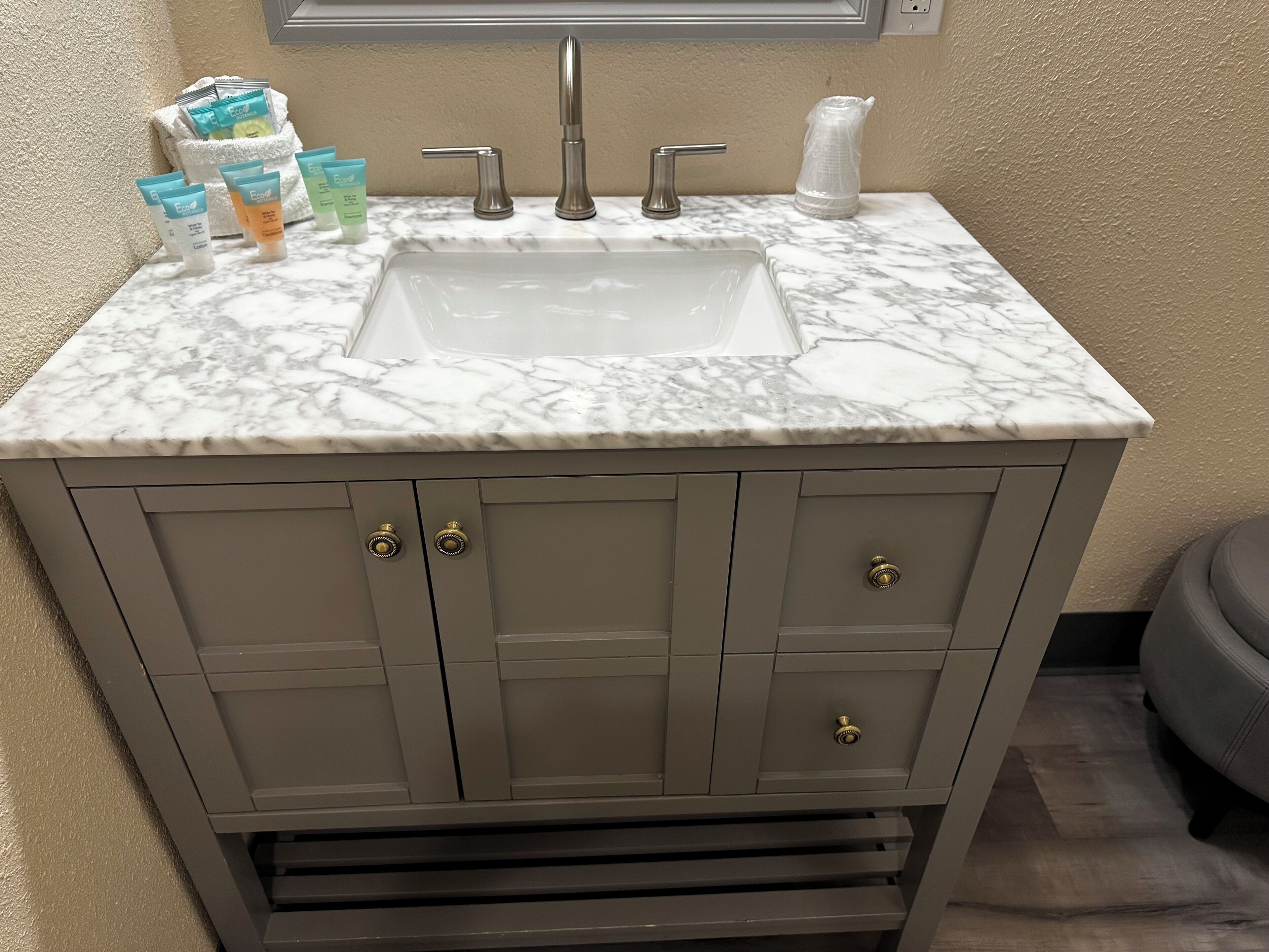 A bathroom with a marble sink, two faucets, and a towel rack.