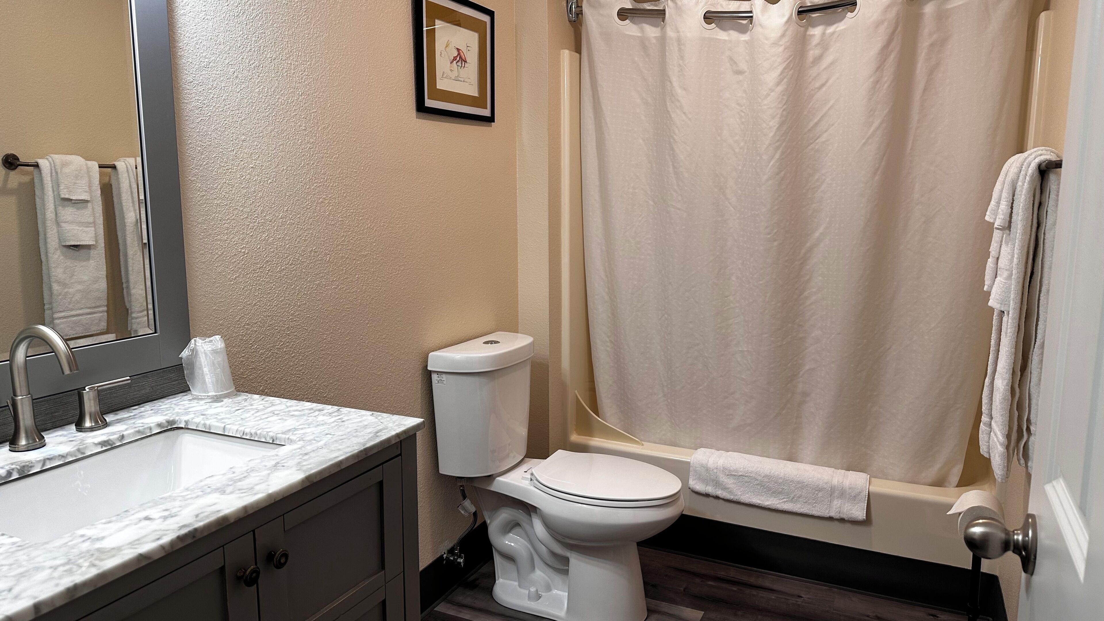 Une salle de bain avec un lavabo en marbre, des toilettes et une baignoire avec un rideau de douche.