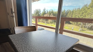 Ein Zimmer mit einer Granitabdeckung und einer Holzbänklage, große Fenster mit Blick auf eine grüne Landschaft und eine Holzterrasse.