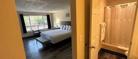 Un dormitorio con una cama grande, un escritorio y una ventana con cortinas.