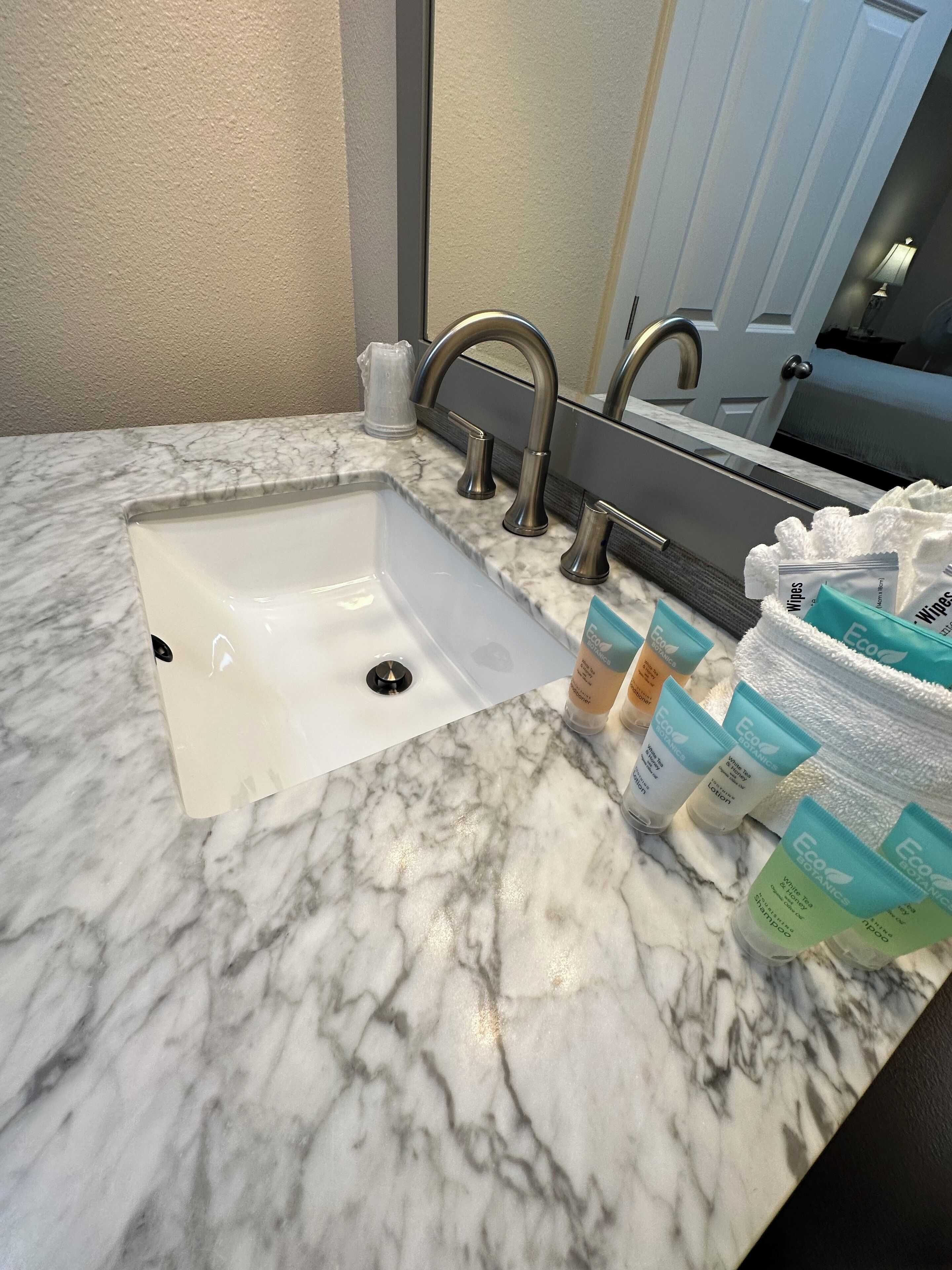 A bathroom sink with a marble countertop, a modern faucet, and a mirror above it.