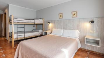 Een slaapkamer met een stapelbed, een eenpersoonsbed, een nachtkastje, een wandplank en een wandlamp.