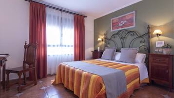 A neatly arranged bedroom with a bed, a chair, a nightstand, and a lamp.