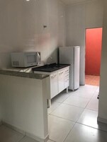 Uma pequena cozinha compacta com micro-ondas, geladeira e pia.