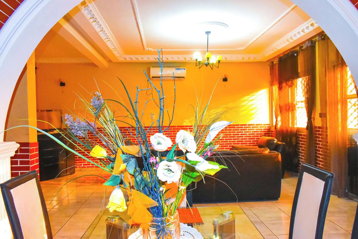 Un coin repas avec une table en verre, des chaises et un vase rempli de fleurs.