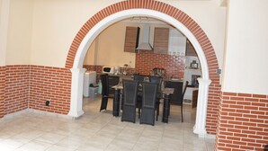 A spacious dining area with a brick wall and white archway leading to a kitchen. - Résidence hôtelière Borel Douala (Douala)