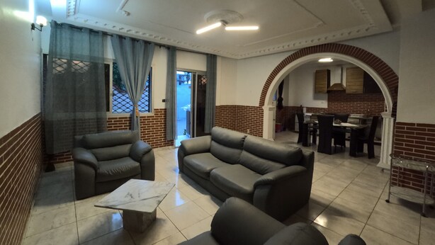 A spacious living area with leather sofas, a marble coffee table, and a brick accent wall. - Résidence hôtelière Borel Douala (Douala)