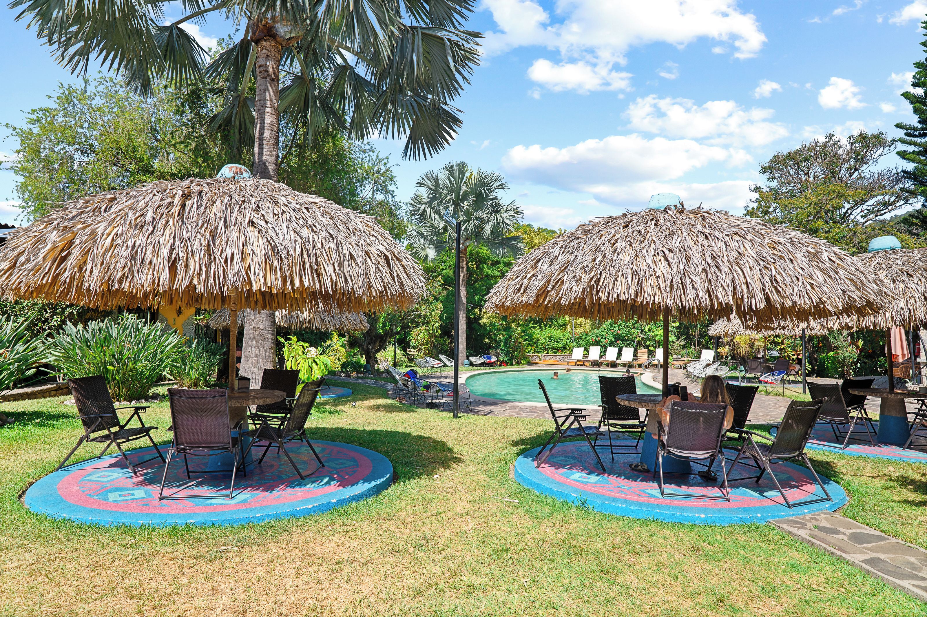 A poolside area with thatched umbrellas, lounge chairs, and a pool.