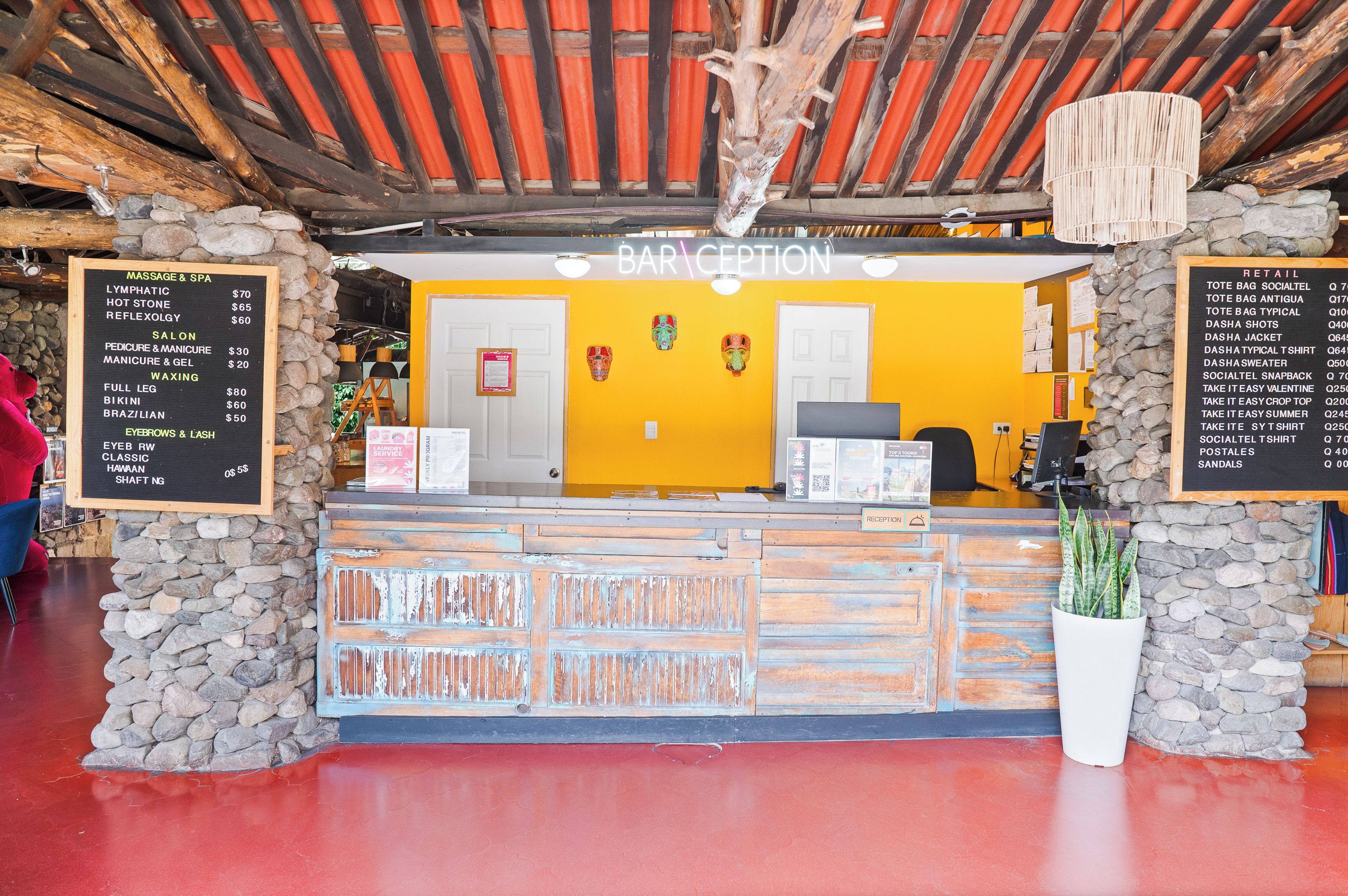 A reception area with a stone wall, a wooden reception desk, and a yellow wall with a reception sign.